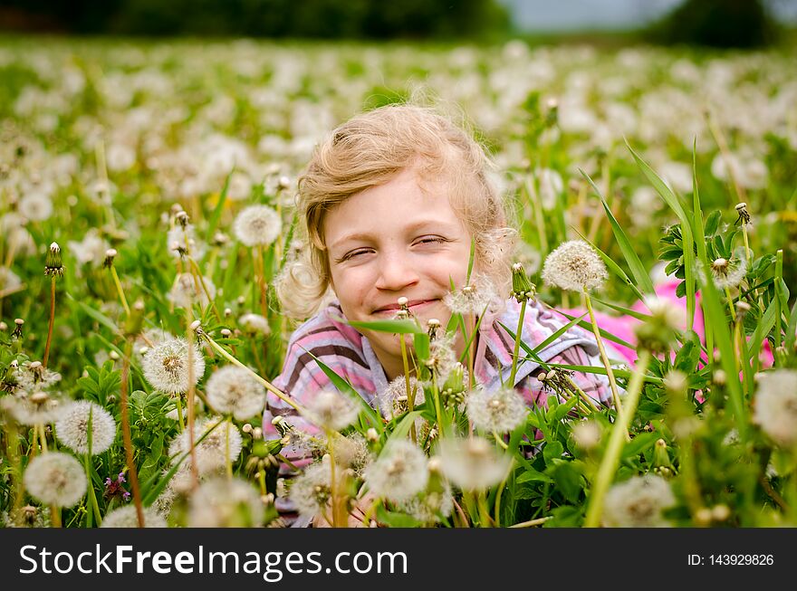 Cute child in blossoming dandelion flower meadow