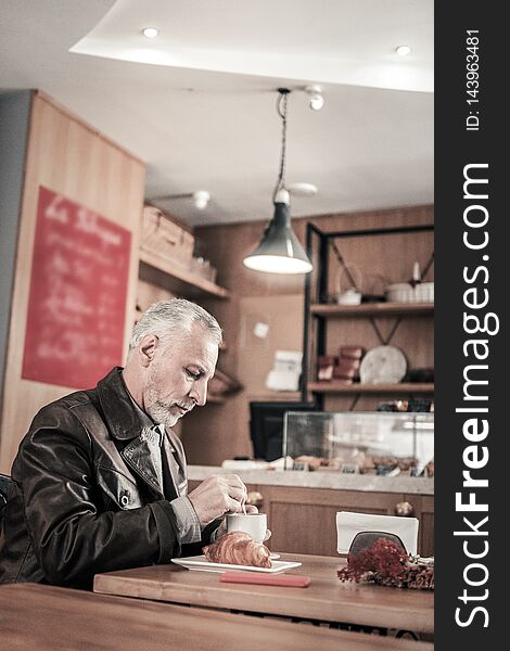 Serious Gray-haired Man Sitting Alone In Cafeteria