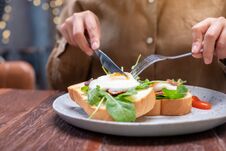 A Woman Eating Breakfast Sandwich With Eggs, Bacon And Sour Cream By Knife And Fork In A Plate Royalty Free Stock Photos A Woman Eating Breakfast Sandwich With Eggs, Bacon And Sour Cream By Knife And Fork In A Plate Royalty Free Stock Photos