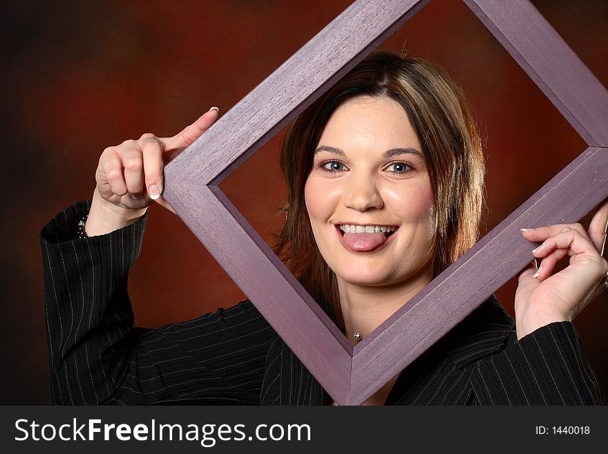 Brunette girl using a picture frame to frame her face. Brunette girl using a picture frame to frame her face