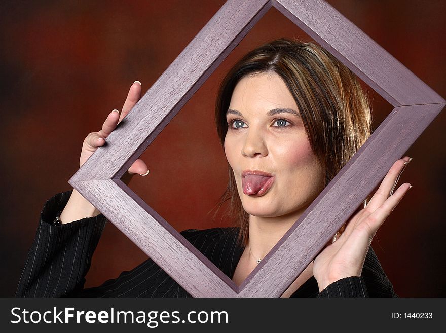 Brunette girl using a picture frame to frame her face. Brunette girl using a picture frame to frame her face