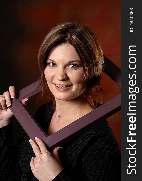 Brunette girl using a picture frame to frame her face. Brunette girl using a picture frame to frame her face