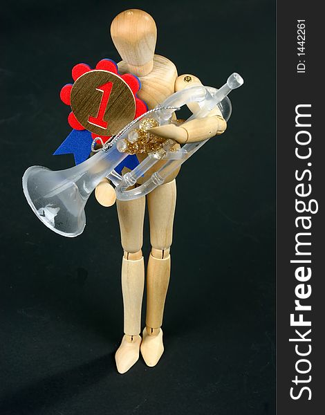 Wooden mannequin holding trumpet and wearing winning ribbon. Wooden mannequin holding trumpet and wearing winning ribbon