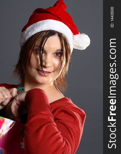 Young santa girl model in front of grey background with shopping bag. Young santa girl model in front of grey background with shopping bag