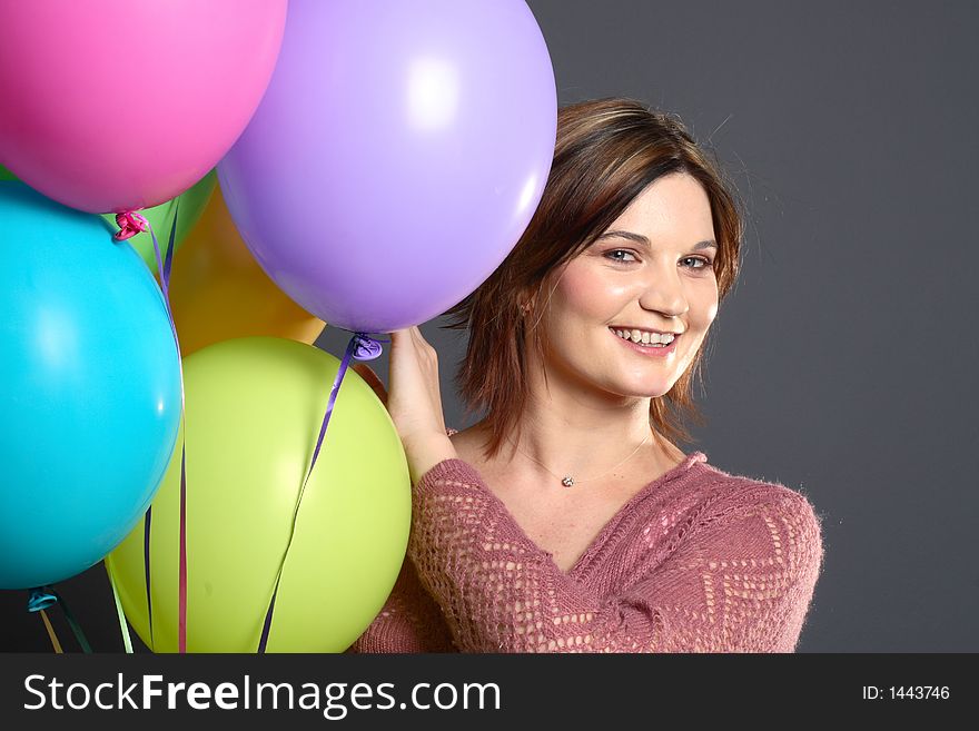 Brunette model with balloons in front of grey background