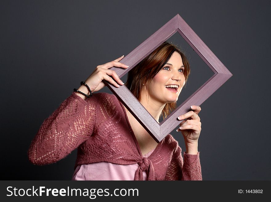 Brunette girl using a picture frame to frame her face. Brunette girl using a picture frame to frame her face