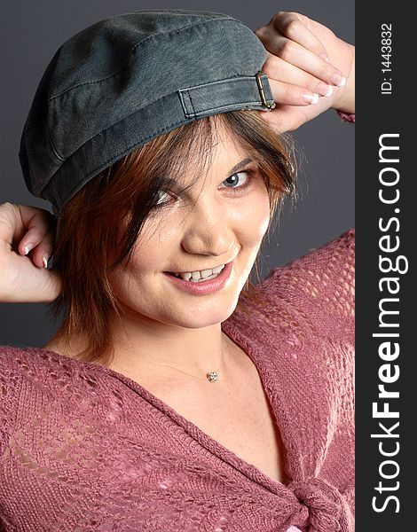 Brunette girl striking a pose with a grey cap in front of grey background. Brunette girl striking a pose with a grey cap in front of grey background