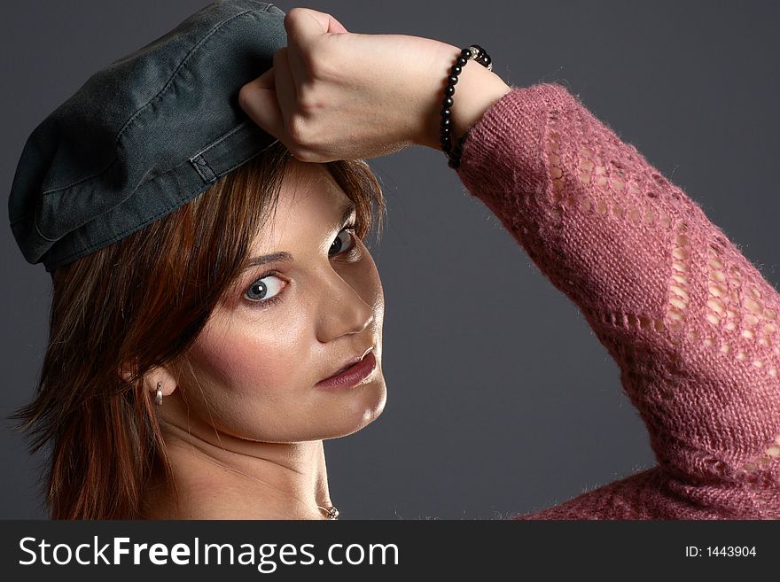 Brunette girl striking a pose with a grey cap in front of grey background. Brunette girl striking a pose with a grey cap in front of grey background