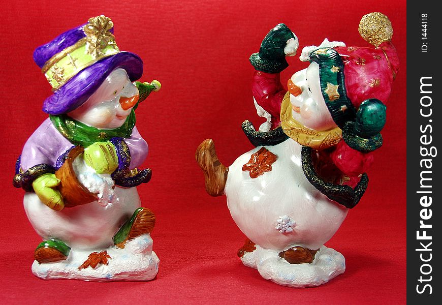 Two funny snowmen in a beautiful red background