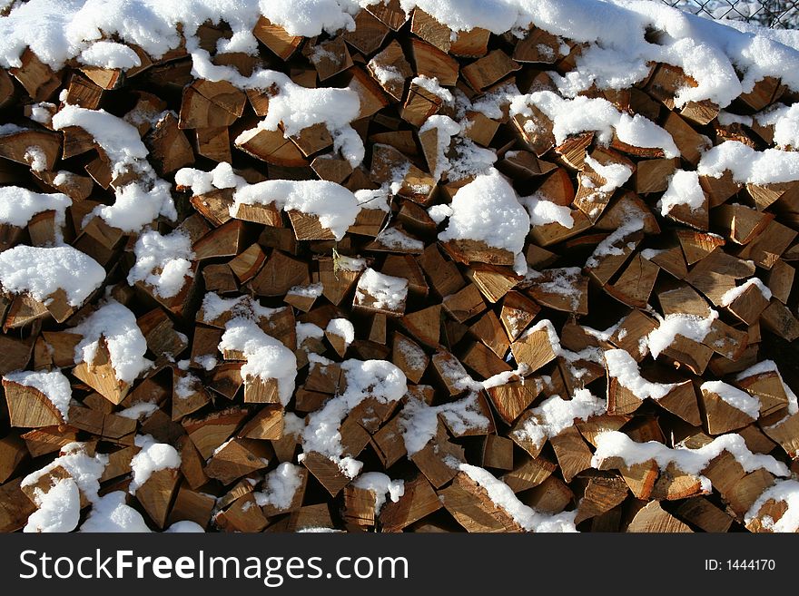 Pile of chopped logs covered with snow