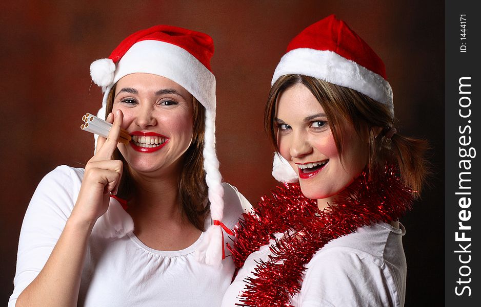 Two girls wearing santa caps one smoking several cigarettes. Two girls wearing santa caps one smoking several cigarettes.