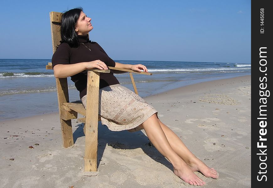 Girl and wooden chair on the beach