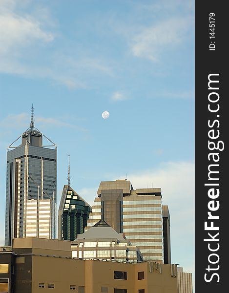 Moon over Perth skyscrapers as sun lights their windows. Moon over Perth skyscrapers as sun lights their windows