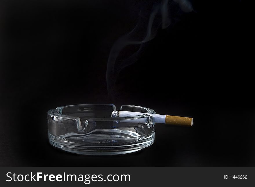 Burning cigarette in ashtray isolated on black background