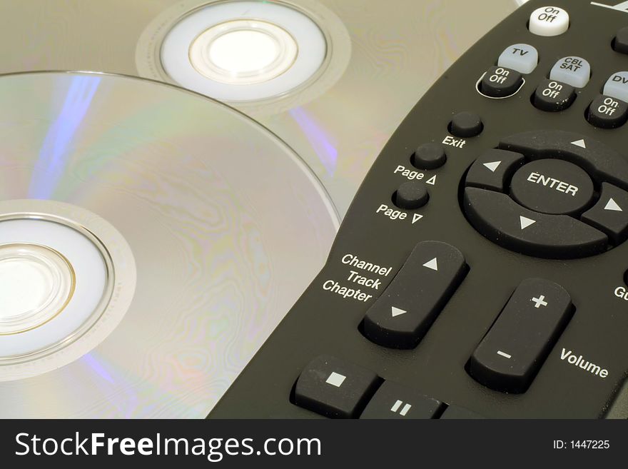 This is a close up image of a TV remote control and DVDs. This is a close up image of a TV remote control and DVDs.