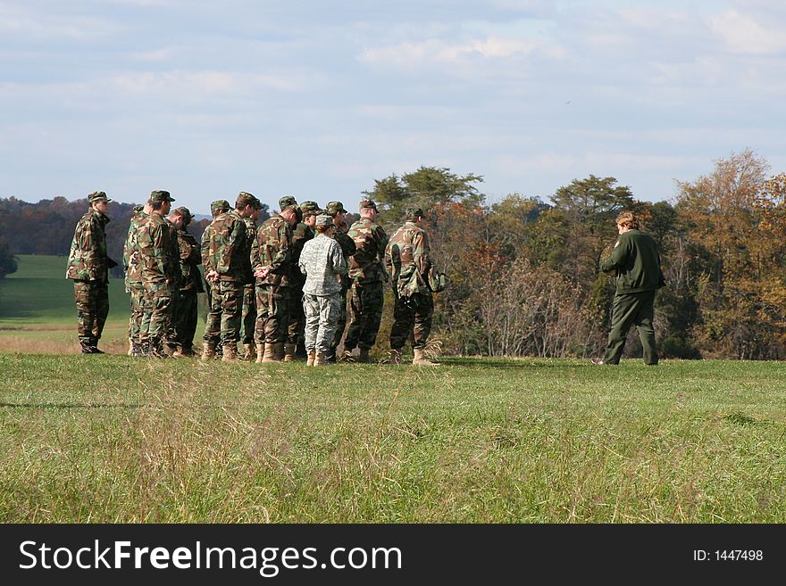 Soldiers in a field listening to their instructions