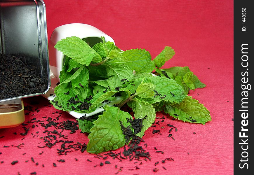 A cup of green tea whit mint leaves on red background