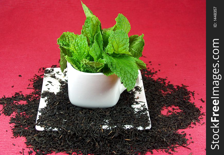 A cup of green tea whit mint leaves on red background