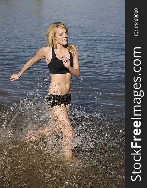 A woman running and cooling off in the water enjoying the refreshing feeling of the water. A woman running and cooling off in the water enjoying the refreshing feeling of the water.