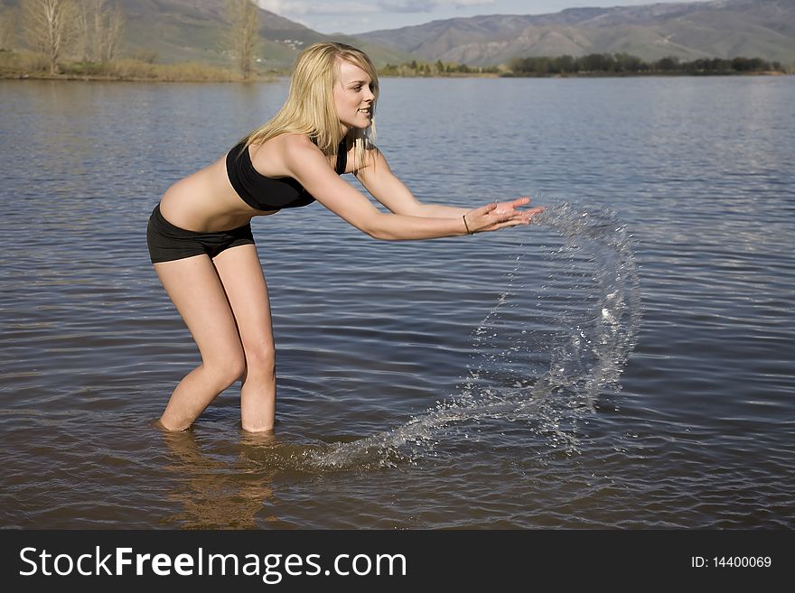 A woman playing in the water by splashing and throwing the water in the air. A woman playing in the water by splashing and throwing the water in the air.