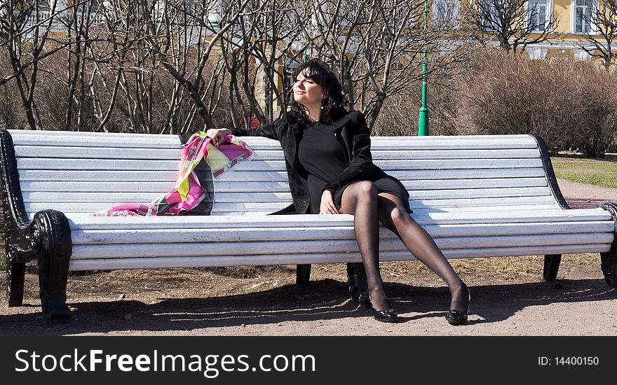 Beautiful woman sitting on a bench in the spring garden