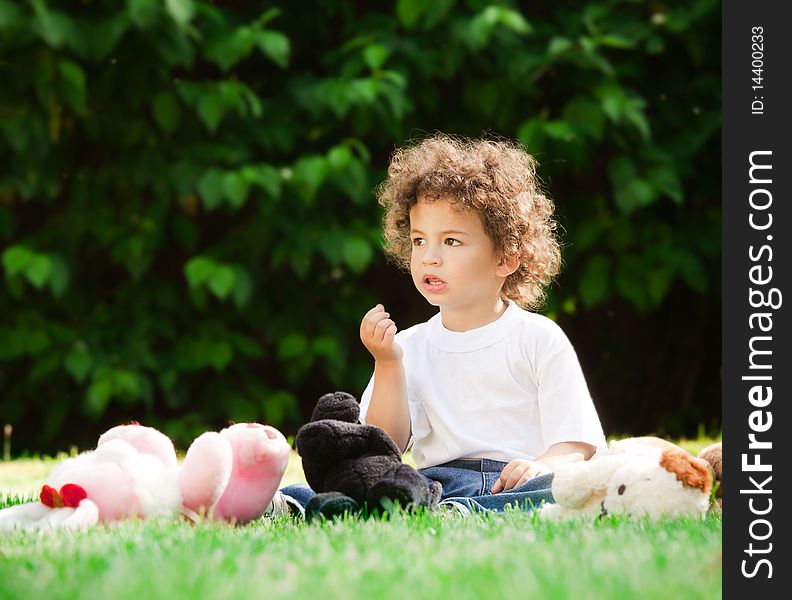 Small boy with curly hair sitting on grass. Small boy with curly hair sitting on grass