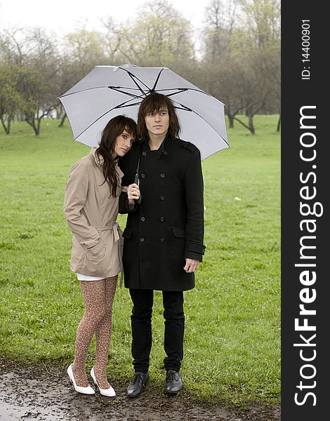 Young couple under umbrella in the park