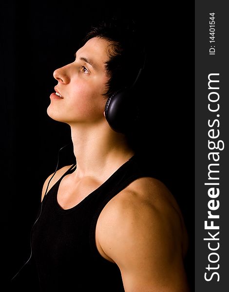 Young Man listening to music with headphones, on black background. Young Man listening to music with headphones, on black background