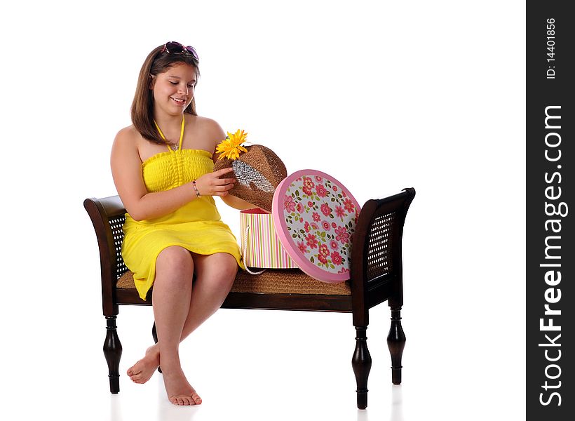 A young teen girl in a yellow sundress, admiring a hat with a big yellow flower.  Isolated on white. A young teen girl in a yellow sundress, admiring a hat with a big yellow flower.  Isolated on white.