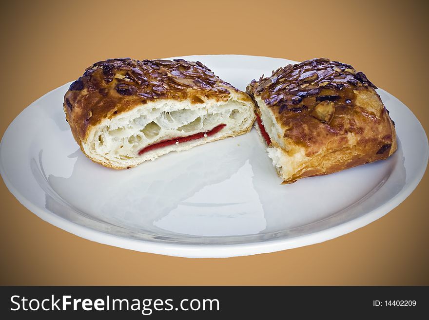 A cut jam filled pastry on a plate with almonds on top. A cut jam filled pastry on a plate with almonds on top