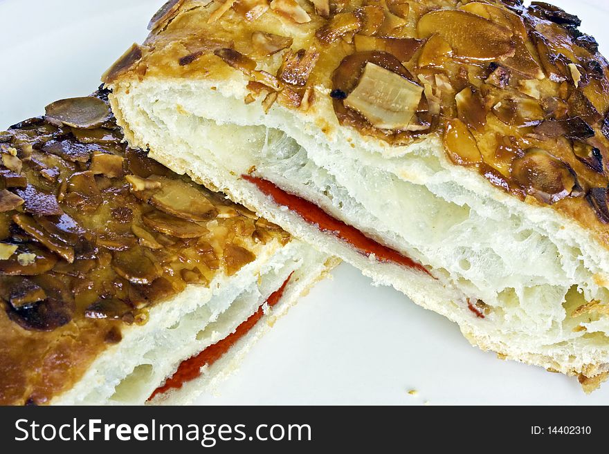 A jam filled cake, cut in half with almonds on top. A jam filled cake, cut in half with almonds on top