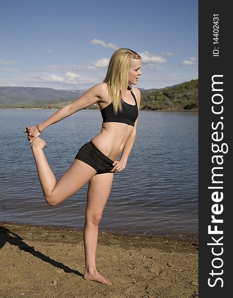 A woman on the beach by the water stretching out her body. A woman on the beach by the water stretching out her body.