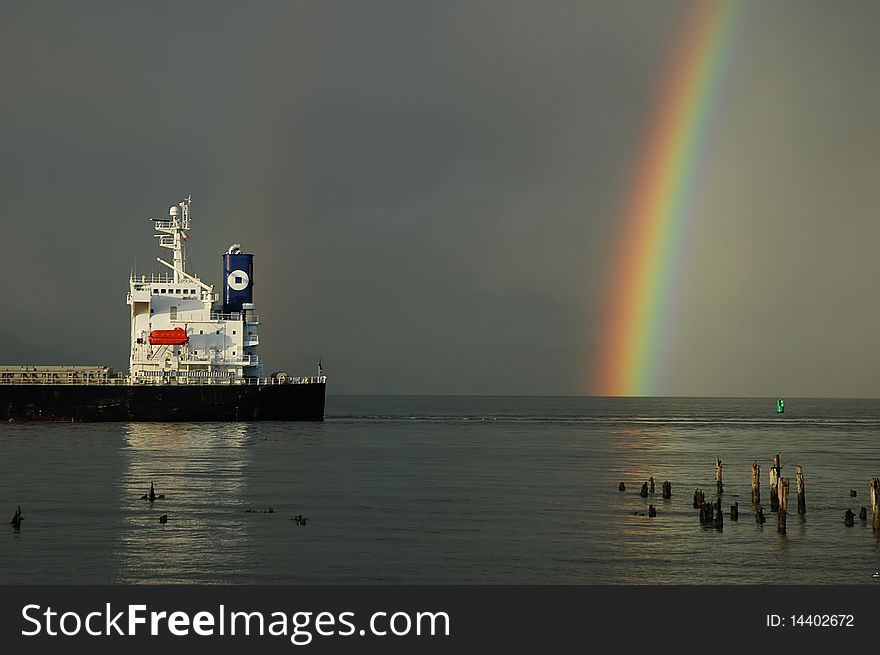 Rainbow and stern of a cargo ship