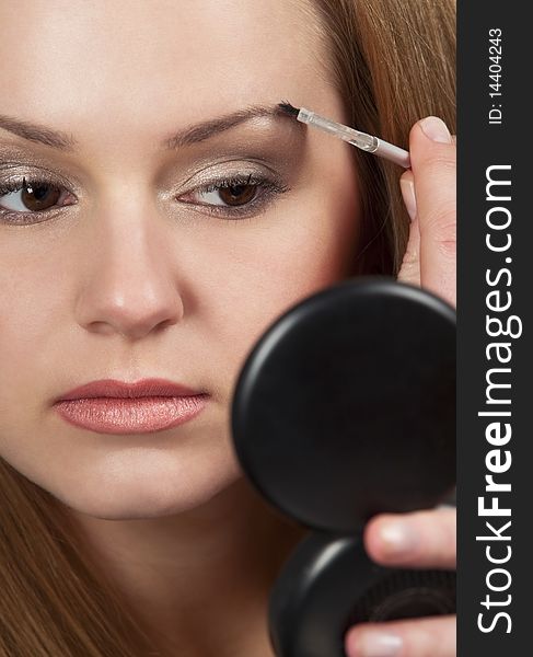 Pretty young woman applying make up.