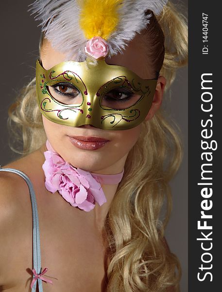 Beautiful woman in carnival mask over gray background