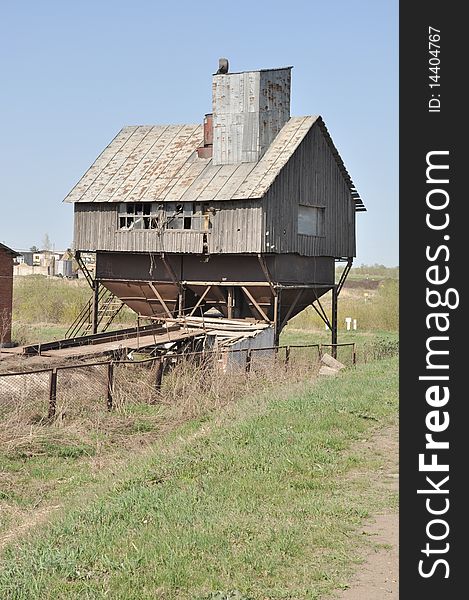 Barn for grain, old mill and grain elevator is at the village road, against a background of blue sky, made of wood and metal. Barn for grain, old mill and grain elevator is at the village road, against a background of blue sky, made of wood and metal