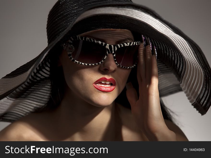 Beautiful model in striped hat and sunglasses on the white background