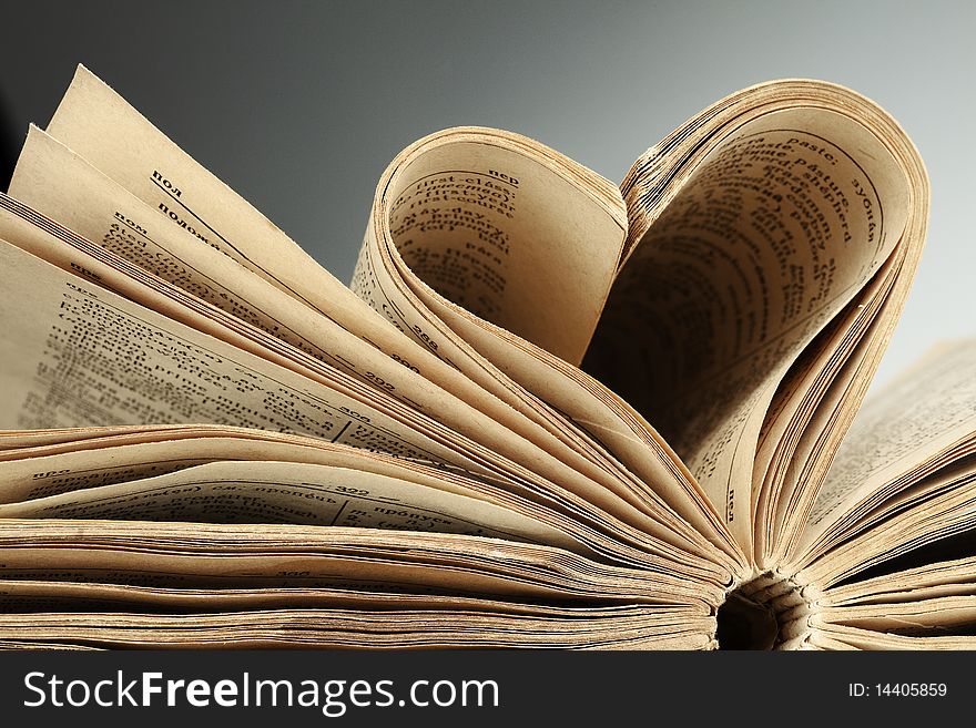 Heart in old book from yellow sheets at black background