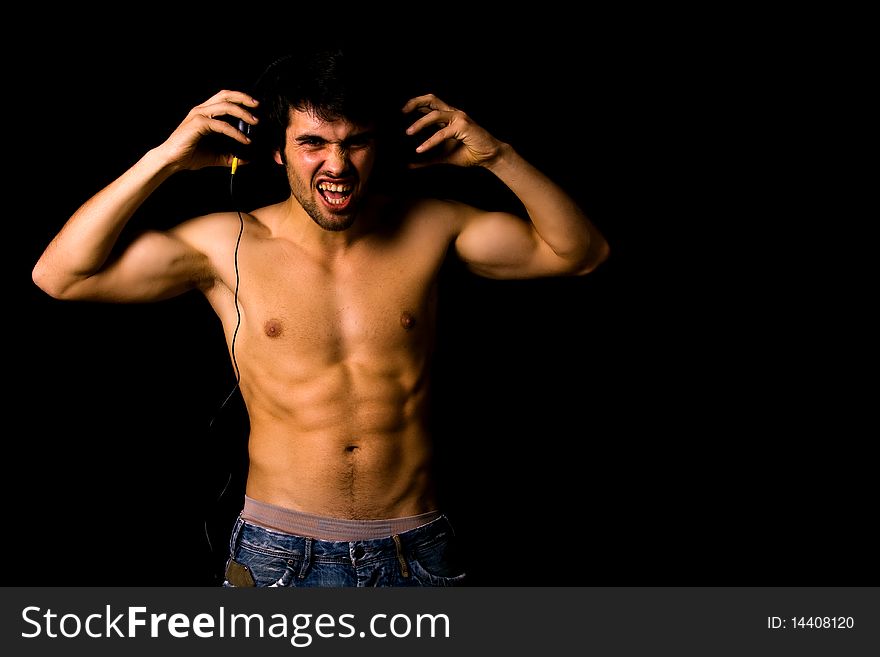 Young Man listening to music with headphones, on black background