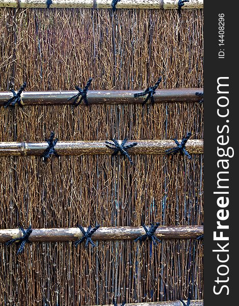 A dark colored bamboo fence in a Shinto temple