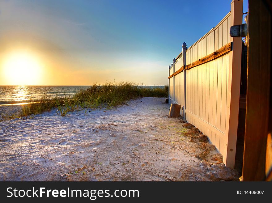 A white fence and white sand on a Florida beach at sunset. A white fence and white sand on a Florida beach at sunset