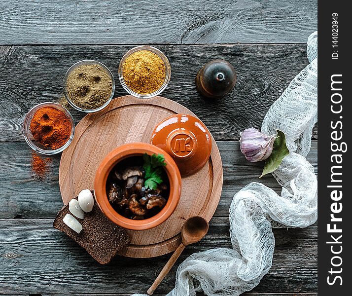 Meat in a saucepan on a wooden stand. Stands on a table with spices