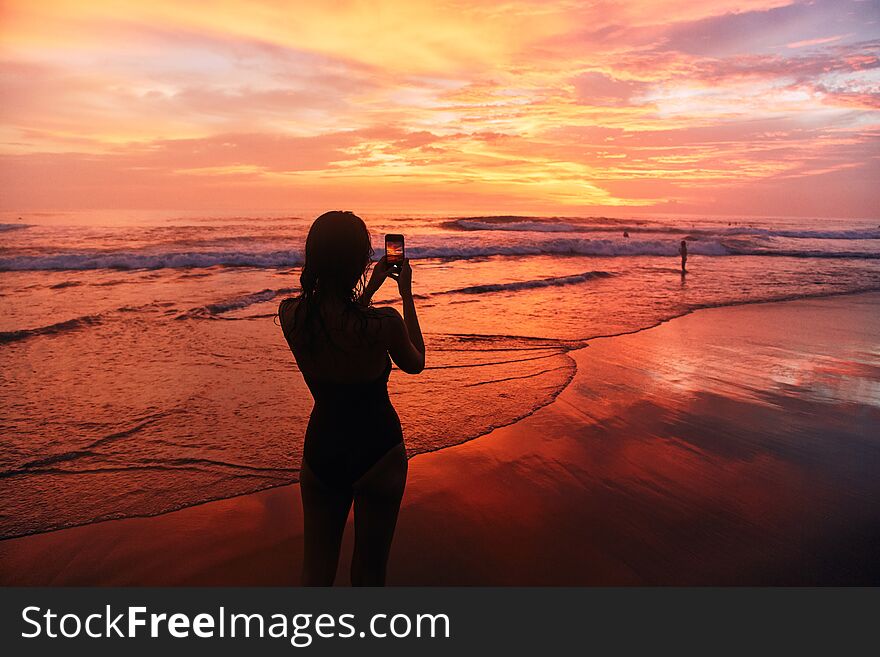 Girl takes a sunset photo on the phone