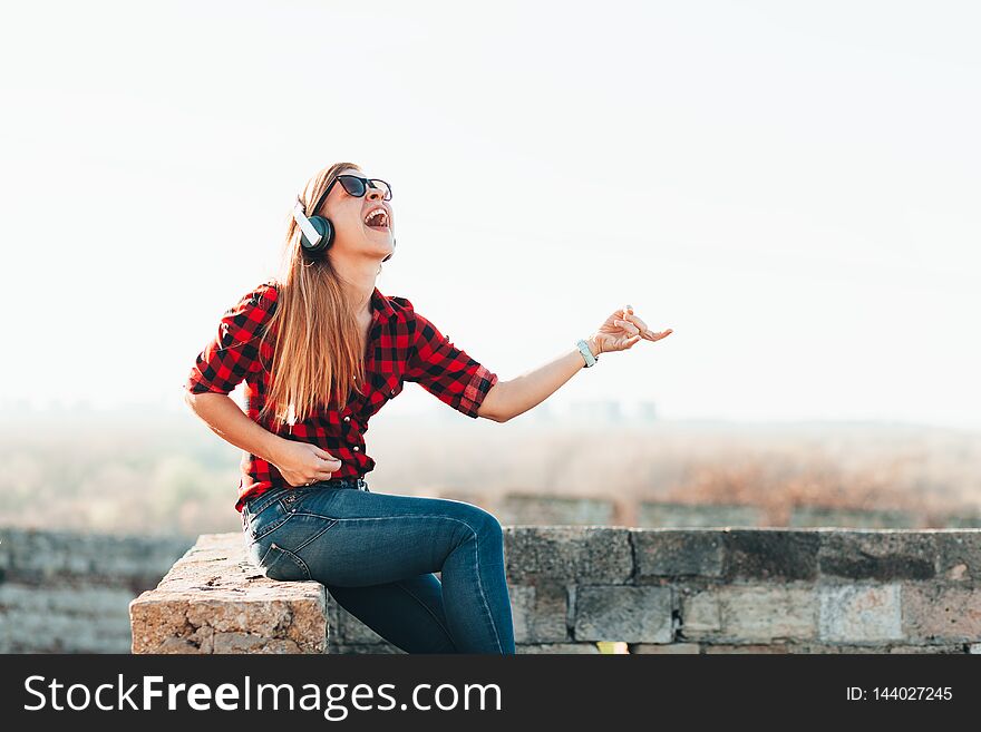 Young Woman Listening To The Music On Headphones Playing Imaginary Guitar