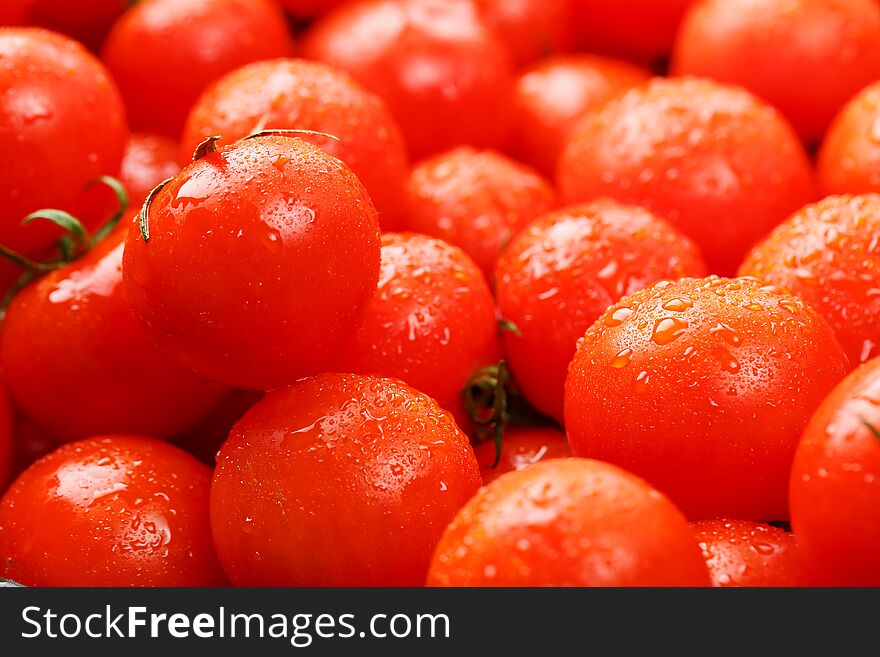 Ripe Red Tomatoes, With Drops Of Dew. Close-up Background With Texture Of Red Hearts With Green Tails. Fresh Cherry Tomatoes With