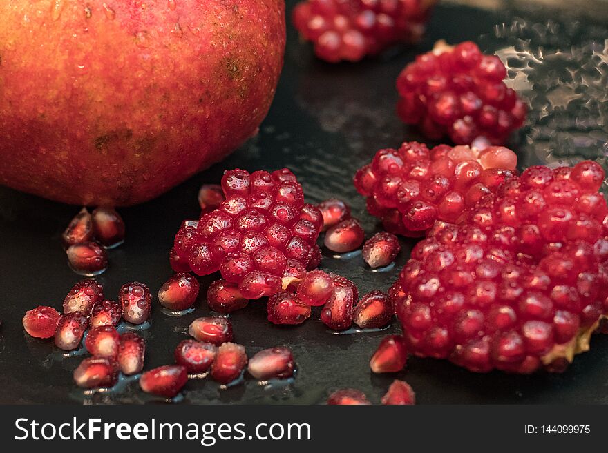 Fresh colorful pomegranates fruits close up on black table