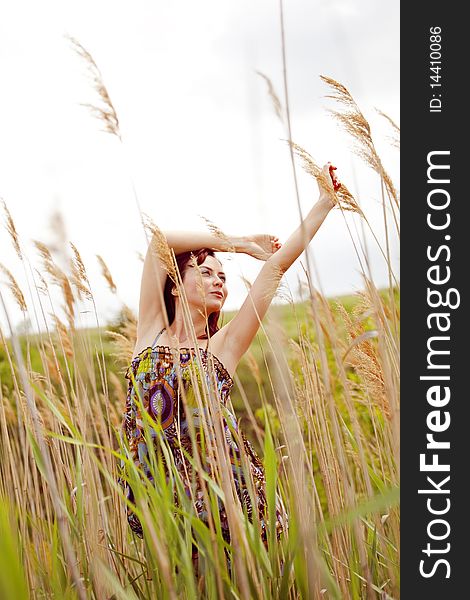 Beautiful young model dancing through the reed in summer. Beautiful young model dancing through the reed in summer