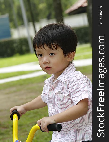 An Asian boy riding a tricycle in a park. An Asian boy riding a tricycle in a park