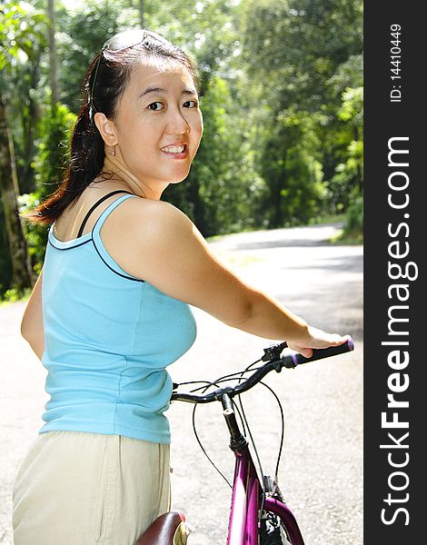 An Asian woman with a bicycle on a road. An Asian woman with a bicycle on a road
