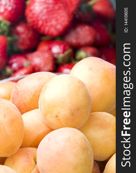 Vertical image of apricots and strawberries on a background